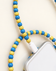 Blue and yellow USB-C beaded cable looped around an iPhone on cream background