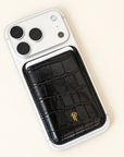 Black Croc Leather Magnetic Phone Wallet with gold logo attached to back of white iPhone