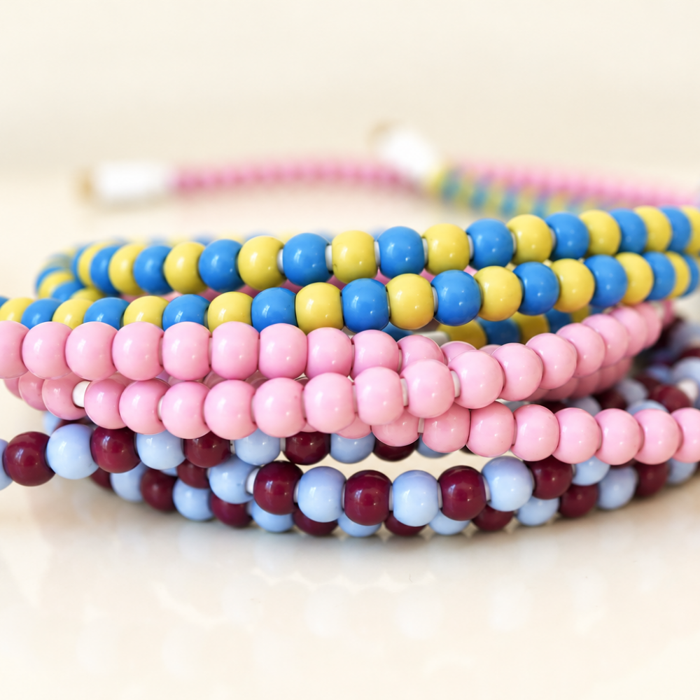 Stacked coils of pink, blue and yellow, and burgundy and light blue beaded charging cables