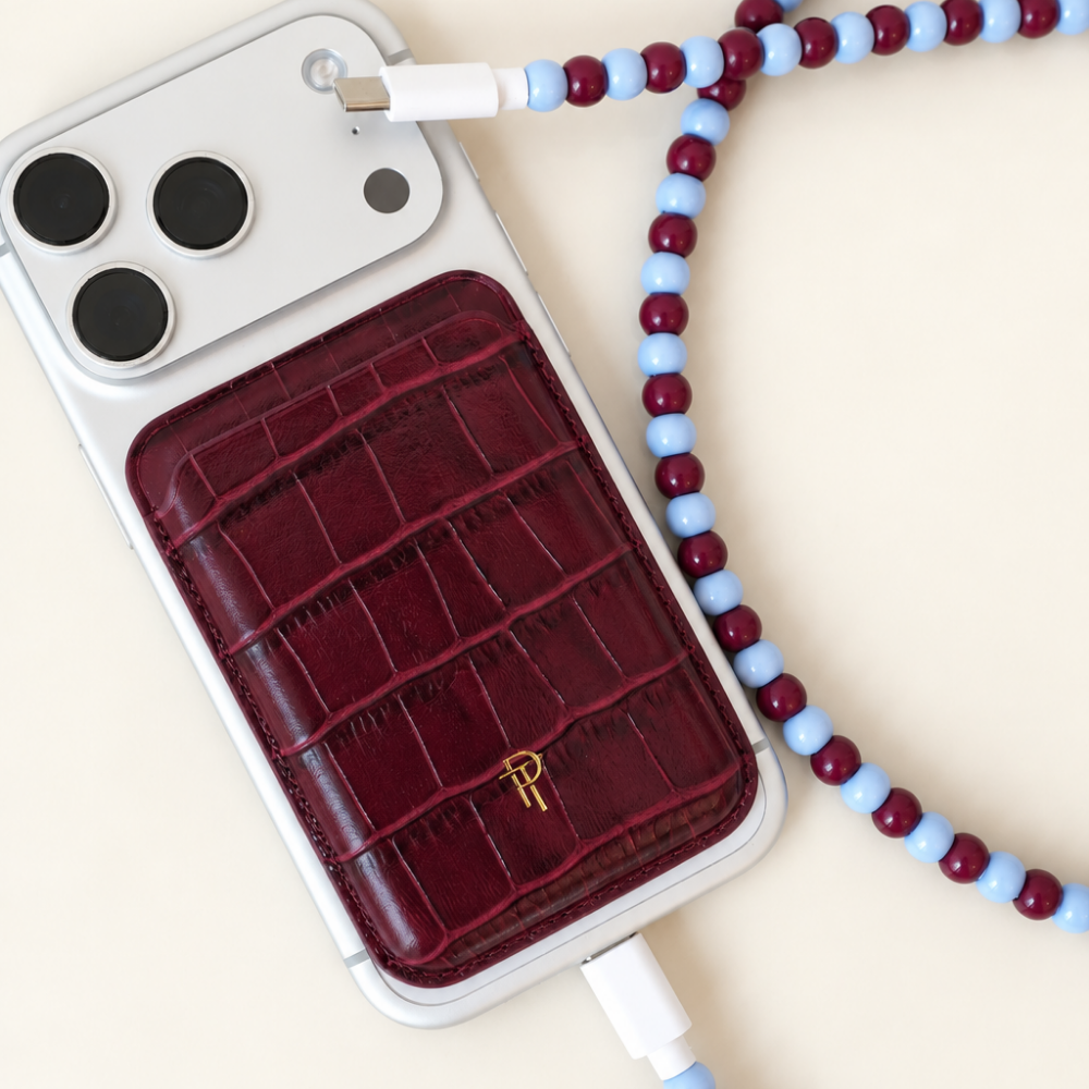 Burgundy and light blue USB-C beaded cable charging an iPhone with a burgundy croc leather magnetic phone wallet