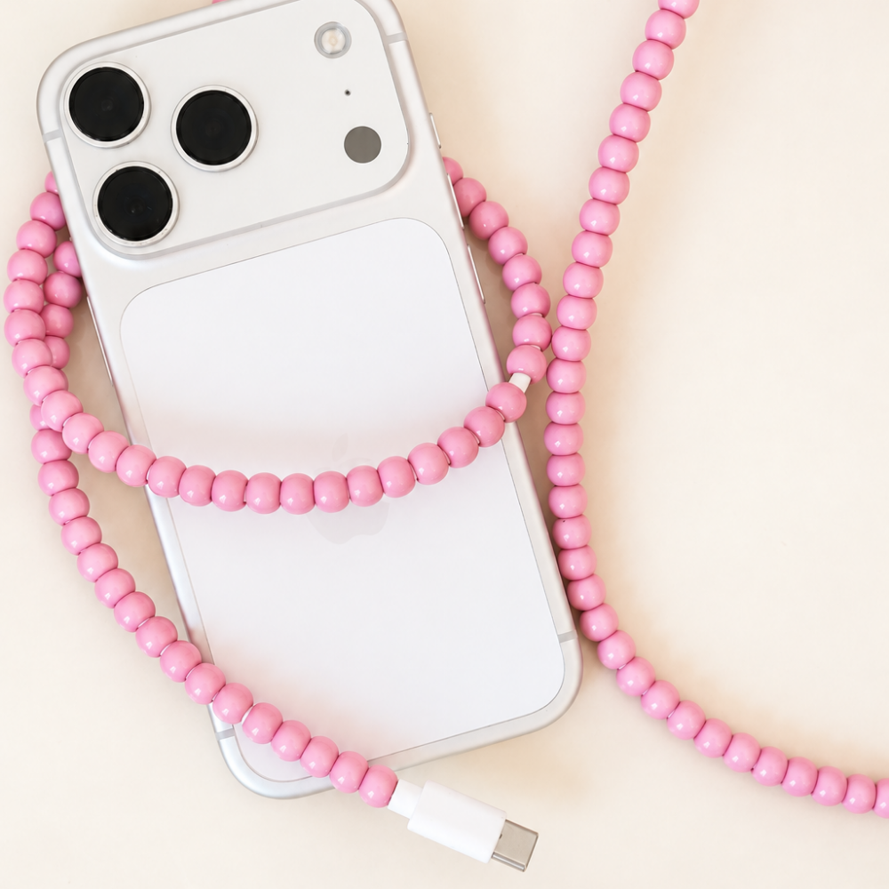 Pink USB-C beaded cable wrapped around an iPhone on cream background