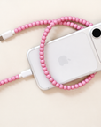 Pink USB-C beaded cable connected to an iPhone on cream background
